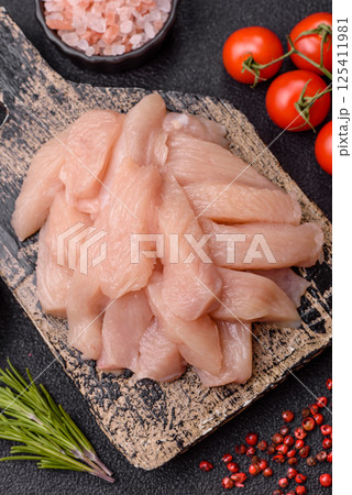 Raw chicken or turkey fillet cut into slices with salt, spices and herbs 125411981