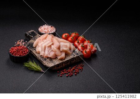 Raw chicken or turkey fillet cut into slices with salt, spices and herbs Raw chicken or turkey fillet cut into slices with salt, spices and herbs 125411982