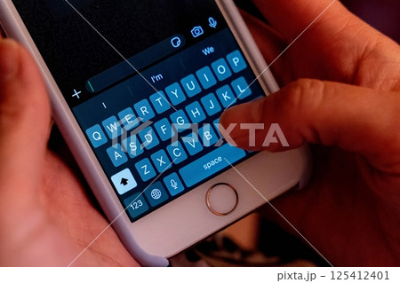 Close up of hands typing on smartphone keyboard in dark environment 125412401