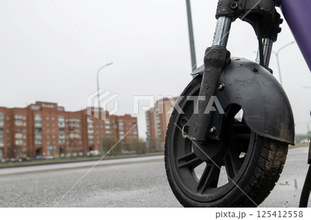 Electric scooter wheel standing on wet asphalt road after rain in city Electric scooter wheel standing on wet asphalt road after rain in city 125412558