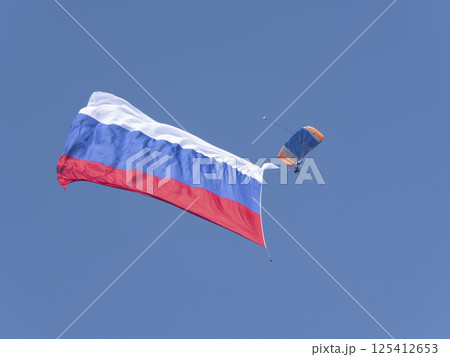 ZHUKOVSKY, RUSSIA - SEPTEMBER 01, 2021: Parachutist with a huge Russian flag in the sky ZHUKOVSKY, RUSSIA - SEPTEMBER 01, 2021: Parachutist with a huge Russian flag in the sky 125412653