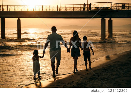 Family Walking on Beach at Sunset Holding Hands Family Walking on Beach at Sunset Holding Hands 125412863