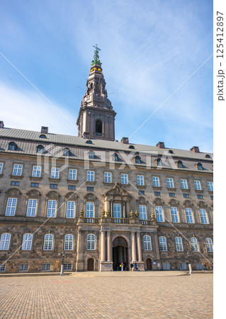 Visitors admire the impressive architecture of Christiansborg Palace in Copenhagen, Denmark. This historic building serves as a key government site on Slotsholmen islet. 125412897