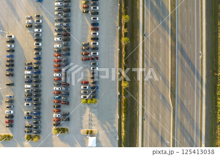 Large parking lot of local dealer with many brand new cars parked for sale on highway roadside. Development of american automotive industry and distribution of manufactured vehicles concept 125413038
