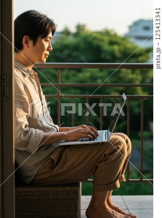 バルコニーで日差しを浴びながら働く日本人男性（ai生成画像） 125413341