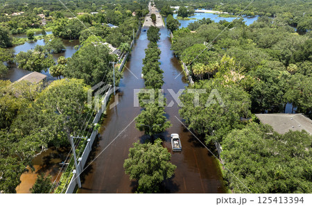 Flooded Florida street with stuck car after hurricane Debby rainfall surrounded with water. Consequences of natural disaster Flooded Florida street with stuck car after hurricane Debby rainfall surrounded with water. Consequences of natural disaster 125413394