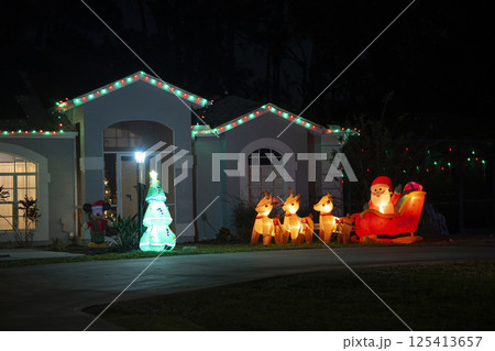 Brightly illuminated Christmas decorations on front yard of Florida family home. Outside decor for winter holidays Brightly illuminated Christmas decorations on front yard of Florida family home. Outside decor for winter holidays 125413657