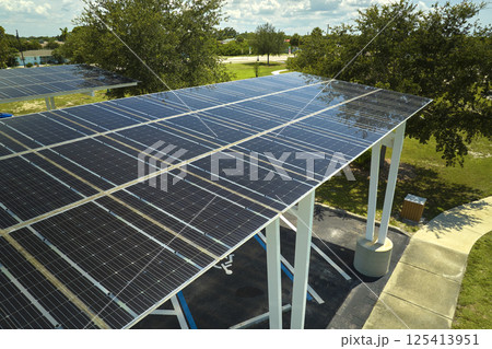 Aerial view of solar panels installed as shade roof over parking lot for parked cars for effective generation of clean electricity. Photovoltaic technology integrated in urban infrastructure Aerial view of solar panels installed as shade roof over parking lot for parked cars for effective generation of clean electricity. Photovoltaic technology integrated in urban infrastructure 125413951