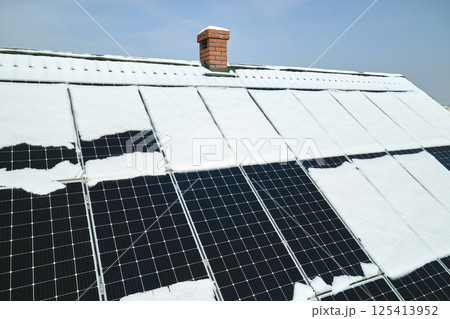 Aerial view of snow melting from covered solar photovoltaic panels installed on house rooftop for producing clean electrical energy. Low effectivity of renewable electricity in nothern region winter 125413952