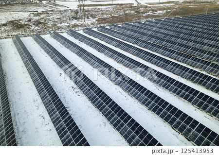 Aerial view of snow melting from covered solar photovoltaic panels at sustainable electric power plant for producing clean electrical energy. Low effectivity of renewable electricity in winter Aerial view of snow melting from covered solar photovoltaic panels at sustainable electric power plant for producing clean electrical energy. Low effectivity of renewable electricity in winter 125413953