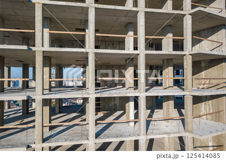 Aerial view of concrete frame of tall apartment building under construction in a city. 125414085