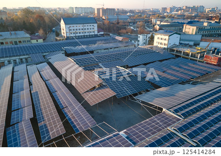 Aerial view of blue photovoltaic solar panels mounted on industrial building roof for producing green ecological electricity. Production of sustainable energy concept Aerial view of blue photovoltaic solar panels mounted on industrial building roof for producing green ecological electricity. Production of sustainable energy concept 125414284