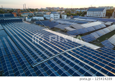 Aerial view of blue photovoltaic solar panels mounted on industrial building roof for producing green ecological electricity. Production of sustainable energy concept Aerial view of blue photovoltaic solar panels mounted on industrial building roof for producing green ecological electricity. Production of sustainable energy concept 125414289