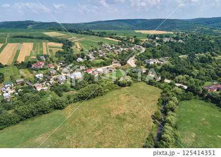 Aerial landscape view of green cultivated agricultural fields with growing crops and distant village houses Aerial landscape view of green cultivated agricultural fields with growing crops and distant village houses 125414351