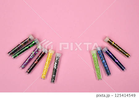 Brightly colored sequins neatly arranged in round containers, resting on a soft pink background for a playful, festive feel. Brightly colored sequins neatly arranged in round containers, resting on a soft pink background for a playful, festive feel. 125414549