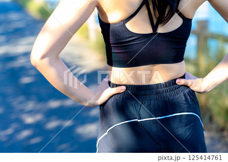 青空の下で運動するかっこいい女性の後ろ姿　背中　ダイエット　エクササイズ　運動　腰に手を当てる 125414761