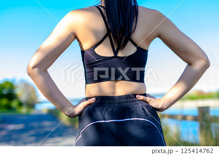 青空の下で運動するかっこいい女性の後ろ姿　背中　ダイエット　エクササイズ　運動　腰に手を当てる 125414762