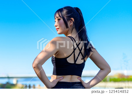 青空の下で運動するかっこいい女性の後ろ姿　振り返る　ダイエット　エクササイズ　運動　トリミングアップ 125414852