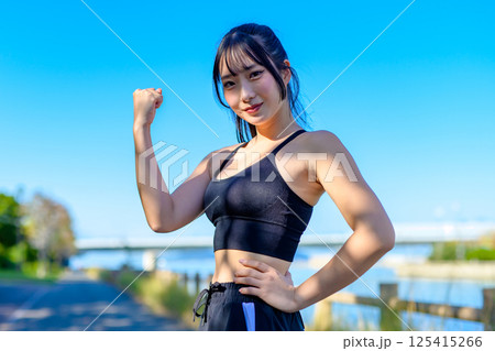 青空の下で運動するかっこいい女性　ガッツポーズ　ダイエット　エクササイズ　運動　トリミングアップ 125415266