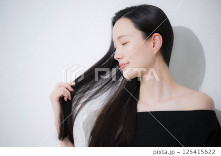 黒髪のロングヘアを触る、美しい若い女性の艶と素肌感が美しいビューティーイメージの横顔のクローズアップ 黒髪のロングヘアを触る、美しい若い女性の艶と素肌感が美しいビューティーイメージの横顔のクローズアップ 125415622