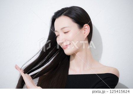 黒髪のロングヘアを触る、美しい若い女性の艶と素肌感が美しいビューティーイメージの横顔のクローズアップ 黒髪のロングヘアを触る、美しい若い女性の艶と素肌感が美しいビューティーイメージの横顔のクローズアップ 125415624