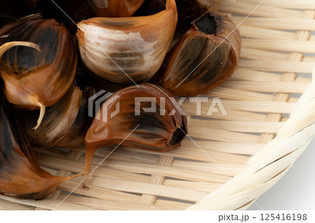 竹ざるに載せた黒にんにく（皮付き）のクローズアップ 125416198