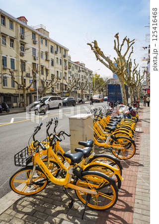 Shanghai, China - 1 April 2025: Yellow bike parking in Pudong. Road, pedestrians, old house, cars. Spring day 125416468