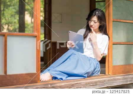 タブレットを片手に思い悩む若い女性 タブレットを片手に思い悩む若い女性 125417825