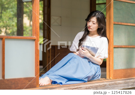 タブレットを片手に思い悩む若い女性 タブレットを片手に思い悩む若い女性 125417826