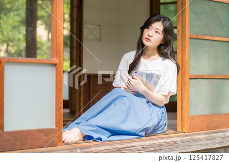 タブレットを片手に思い悩む若い女性 タブレットを片手に思い悩む若い女性 125417827