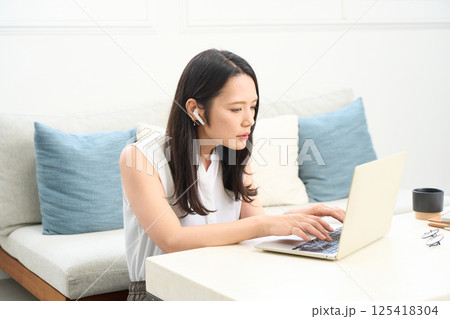 パソコン画面を真剣に見る女性 リビング ワンルーム パソコン画面を真剣に見る女性 リビング ワンルーム 125418304
