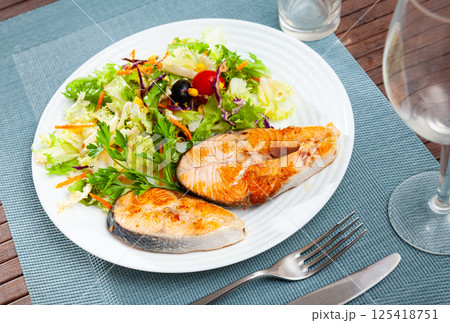Two fried salmon steaks with vegetable salad Two fried salmon steaks with vegetable salad 125418751
