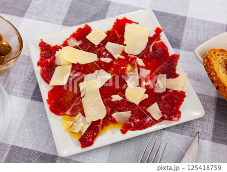 Beef carpaccio with grated cheese served on plate 125418759