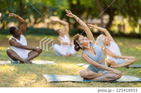 Group of athletic people of different nationalities exercise together in park - stretching their bodies Group of athletic people of different nationalities exercise together in park - stretching their bodies 125418933