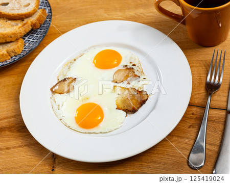 Appetizing breakfast with scrambled eggs and juicy bacon closeup 125419024