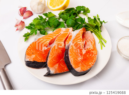 Raw salmon steaks on plate, over white background Raw salmon steaks on plate, over white background 125419088