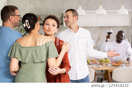 Smiling woman giving greeting kiss to bestie at dinner party 125419222