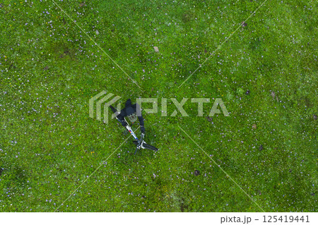 Aerial view of woman riding mountain bike on flowering grassland mountain trail 125419441