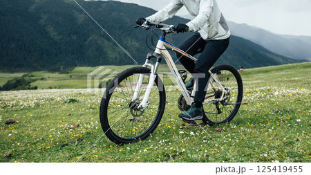 Riding mountain bike on flowering grassland mountain top 125419455