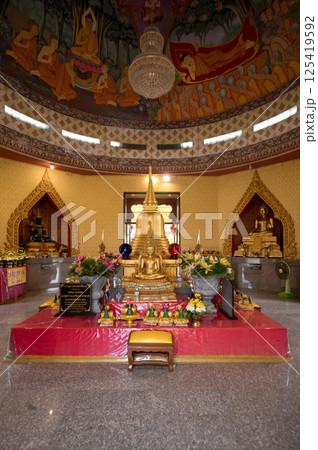 Nakhon Sawan, Thailand, November 11, 2023, Explore the serene interior of Wat Khiriwong featuring a central Buddha statue adorned with flowers and vibrant decorations 125419592
