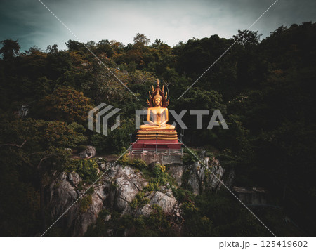 Nakhon Sawan, Thailand, November 12, 2023, Golden Buddha statue overlooking lush greenery at Wat Chong Khae 125419602