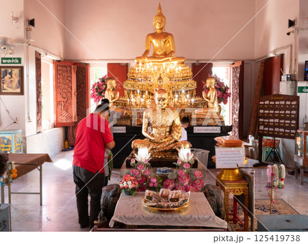 January 11, 2025, Wat Sattahip, Golden Buddha statue in temple with worshippers engaged in prayer and offerings during daylight January 11, 2025, Wat Sattahip, Golden Buddha statue in temple with worshippers engaged in prayer and offerings during daylight 125419738