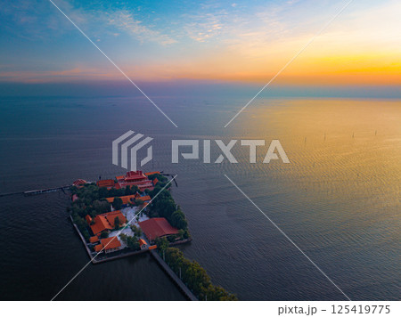 Samut Prakan, Thailand, January 19, 2025, Scenic view of Wat Khun Samutrawat at sunset with tranquil waters reflecting the colorful sky 125419775
