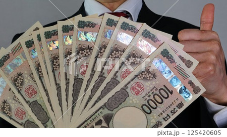 沢山の新一万円札を持ちポーズをするビジネスマン	 125420605