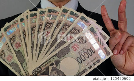 沢山の新一万円札を持ちポーズをするビジネスマン	 125420606