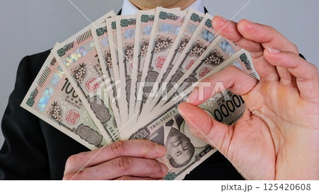 新一万円札を持ちポーズをするビジネスマン	 125420608
