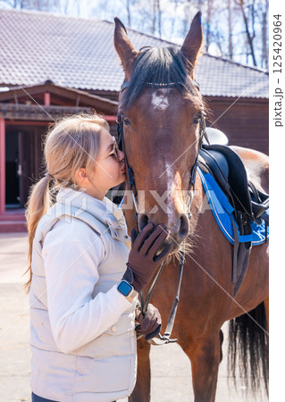 Young woman posing with a horse at a farm. Concept of femininity and strength in harmony with nature. 125420964