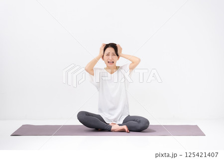 ヨガをする女性　ミドル　頭を抱える 125421407