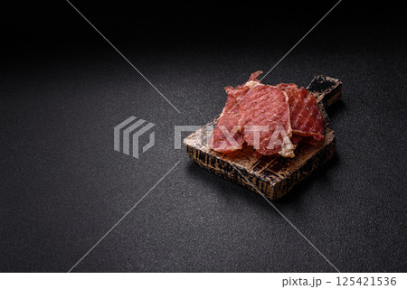 Jerky, dried pork meat slices with salt and spices 125421536