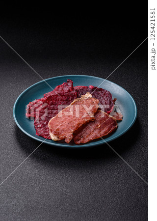 Jerky, dried pork meat slices with salt and spices Jerky, dried pork meat slices with salt and spices 125421581
